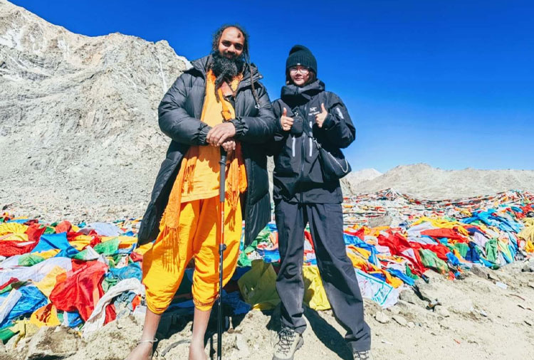 Pilgrims standing near Mount Kailash with prayer flags in the background.